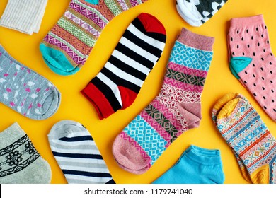 Multi-colored socks on a yellow background. View from above. Many different socks for cold seasons. Socks are scattered on a bright background. Clothes in the form of socks.