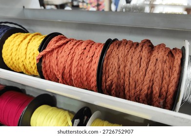 Multicolored spools of thread arranged in a composition on a store shelf, suitable for sewing, needlework, tailoring, textile production, and creative design.