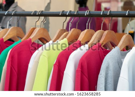 Multi-colored sweaters on wooden hangers in a women's clothing store close-up.