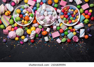 Multicolored Sweet And Bright Dragee, Candies, Lollipops, Marshmallows For Fun Party On Black Marble Background