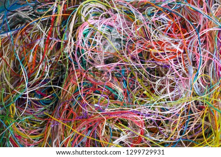 Multi-colored tangled threads abstract texture pattern background. Macro shot of colorful needlecraft silk thread ropes. Colored natural thread pile for sewing clothe scattered randomly like spaghetti