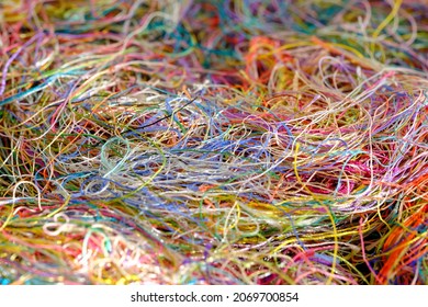 Multi-colored tangled threads background. Macro or close up of colorful tangled threads. Needlecraft silk thread ropes. Colored natural thread pile for sewing cloth scattered randomly like spaghetti.