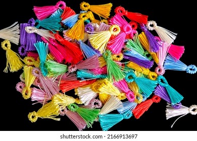 Multi-colored tassels on black background. Close-up of colorful thread tassels heap or pile. Top or above view of beautiful auxiliary materials for ornament decoration or jewelry making.