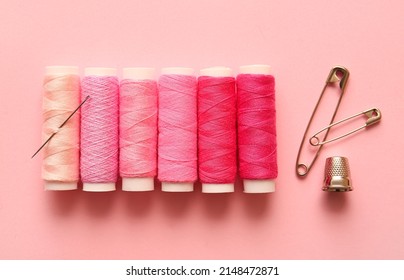 Multicolored thread spools, safety pins and thimble on color background