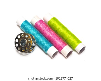 Multi-colored Threads And A Metal Bobbin On A White Background. Sewing Machine Spool Arranged.