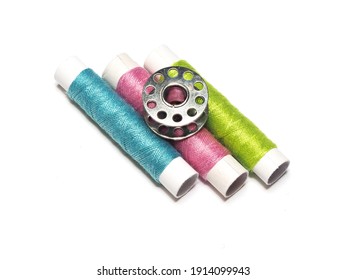 Multi-colored Threads And A Metal Bobbin On A White Background. Sewing Machine Spool Arranged.