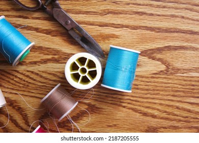 Multicolored threads and old scissors scattered on a wooden table, retro scissors, flat lay, copy space. - Shutterstock ID 2187205555