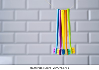 Multi-colored toothbrushes hanging on a thread