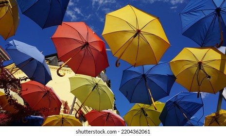 Multi-colored Umbrellas Overhead Against The Blue Sky.                               