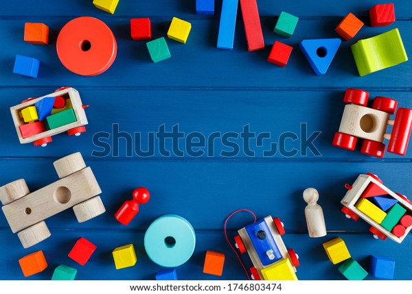 Multicolored wooden toys cubes,\
pyramid and cars on classic blue background. Set colorful toys for\
games in kindergarten, preschool kids. Close up, top view, copy\
space
