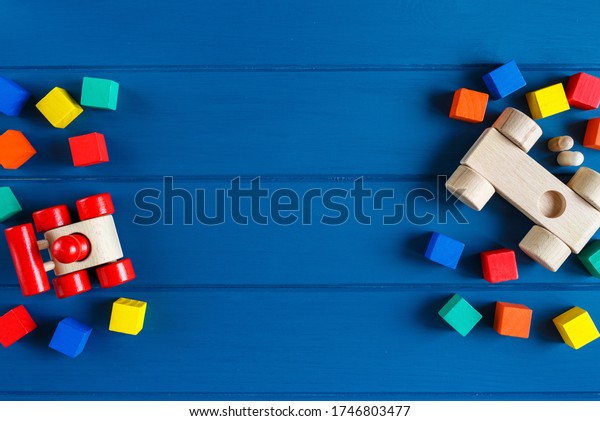 Multicolored wooden toys cubes,\
pyramid and cars on classic blue background. Set colorful toys for\
games in kindergarten, preschool kids. Close up, top view, copy\
space