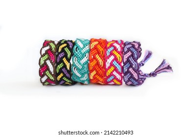 Multicolored woven DIY friendship bracelets Pigtail handmade of embroidery bright thread with knots isolated on white background