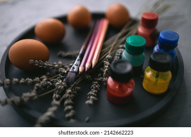 Multicolour paints and brushes on the plate with eggs. Colouring eggs for easter holiday concept. - Shutterstock ID 2142662223