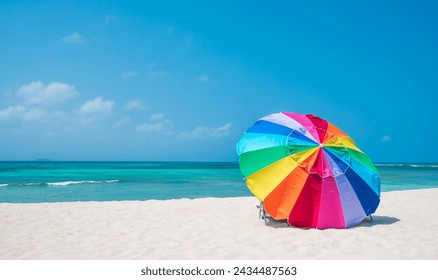 Multicolour vibrant rainbow beach umbrella on a beautiful hot and clear sunny day, with cruise ship on the horizon, turquoise water, Arashi Beach, Aruba, Caribbean Sea. Photo taken in February 2024. - Powered by Shutterstock