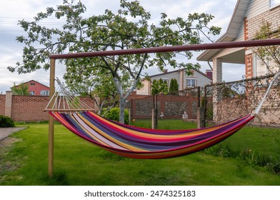 Multicoloured empty hammock in the yard of a residential  - Powered by Shutterstock