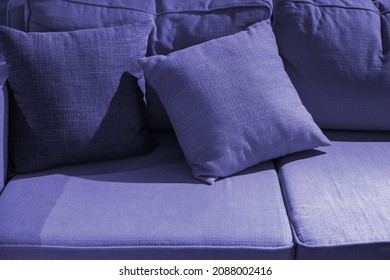 Multicoloured pillow on yellow sofa background. New 2022 trending PANTONE 17-3938 Very Peri color
