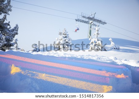 Multicoloured reflections on the snow and skiing lift behind them