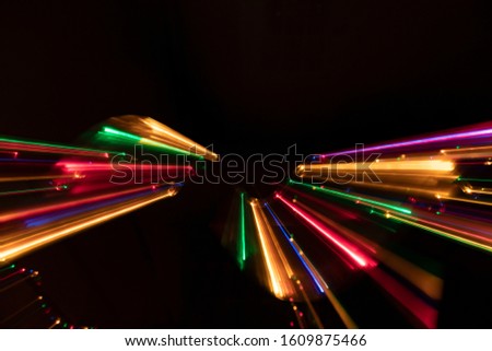 Multicoloured splash of sharp light trails in a zoom out composition on dark background. Blurred and sharp light diffraction trails.