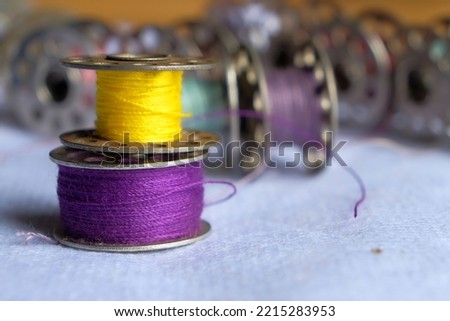 Multicoloured threads on the bobbin from the sewing machine on a blurred background from the other bobbins