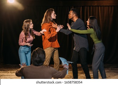 multicultural actors and actresses rehearsing fight on stage in theatre