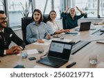 Multicultural business people engaged in a meeting around a conference table in a modern office. They are collaborating and discussing strategies, fostering a productive and friendly atmosphere.