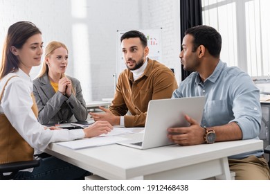 Multicultural Business People Sitting Near Laptop While Working In Office