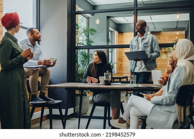 Multicultural Business Professionals Having A Group Discussion During A Meeting In A Modern Office. Team Of Diverse Businesspeople Sharing Creative Ideas In An Inclusive Workplace.