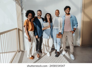 Multicultural business professionals in a modern office. Dressed in business casual attire, they smile and look at the camera. This diverse team embodies teamwork and success in a thriving startup. - Powered by Shutterstock