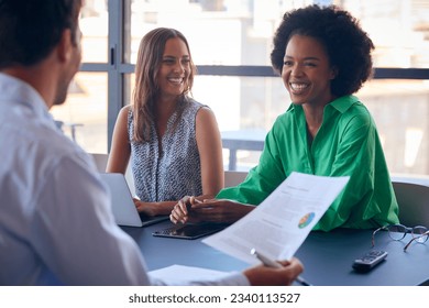 Multi-Cultural Business Team Meeting Around Office Boardroom Table With Laptops Discussing Documents - Shutterstock ID 2340113527