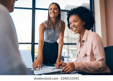 Multi-Cultural Business Team Meeting Around Office Boardroom Table With Laptops Discussing Documents - Shutterstock ID 2340113541