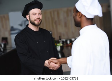multicultural chefs shaking hands at restaurant kitchen