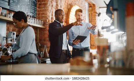 Multicultural Coffee Shop Owners Meeting Behind the Counter and Working on Tablet Computer and Checking Inventory in a Cozy Loft-Style Cafe. Successful Restaurant Managers and Barista at Work. - Shutterstock ID 1882428625