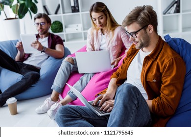 Multicultural Colleagues Working On Startup Project In Office And Sitting On Bean Bag Chairs