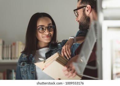 multicultural couple looking at each other in library