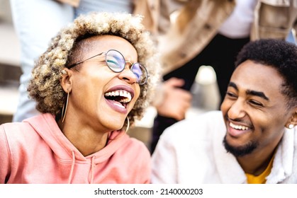 Multicultural couple on genuine laughter - Life style concept with happy multiracial friends having fun together out side - Trendy college students enjoying break time at campus - Warm vivid filter - Shutterstock ID 2140000203