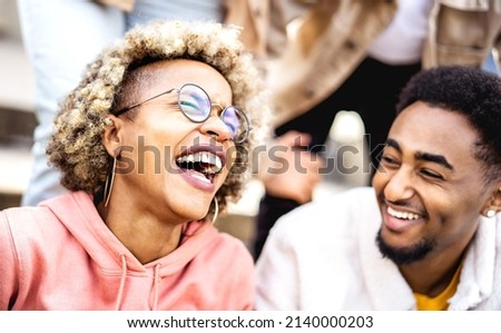 Multicultural couple on genuine laughter - Life style concept with happy multiracial friends having fun together out side - Trendy college students enjoying break time at campus - Warm vivid filter