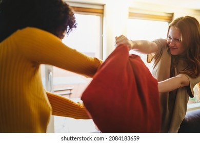 Multicultural Couple Of Young Girlfriends Fighting With Pillows For Fun - Concept Of Lesbian Woman In Domestic Partnership Having Fun And Also Difficulties In Relations.