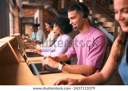 Multi-Cultural Customer Support Or Telesales Team In Modern Open Plan Office Wearing Headsets
