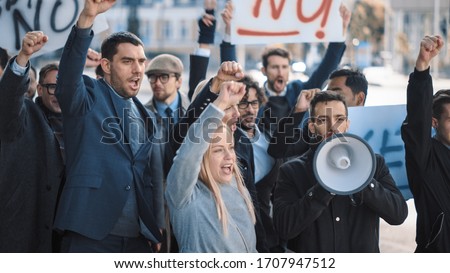 Multicultural Diverse Office Managers and Business People Picketing Outside on a Street. Men and Women Screaming for Justice, Holding a Megaphone, Picket Signs and Posters. Economic Crisis Strike.