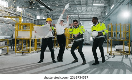 Multicultural engineers dancing at modern manufacturing factory and clapping hands. Employees in safety hard hats celebrating succsess at background of welding sparks flying. - Powered by Shutterstock