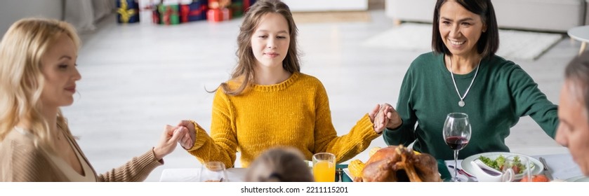 Multicultural Family Holding Hands Near Tasty Thanksgiving Dinner On Table At Home, Banner