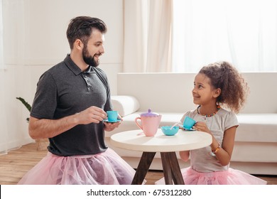 multicultural father and little daughter having tea party at home - Powered by Shutterstock