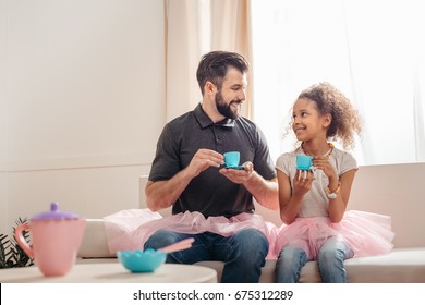 multicultural father and smiling daughter having tea party at home - Powered by Shutterstock