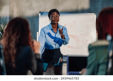 Multicultural female manager having briefing and discussing business strategy and marketing ideas at meeting room with her team. Professional african american leader presenting new business plan. - Powered by Shutterstock