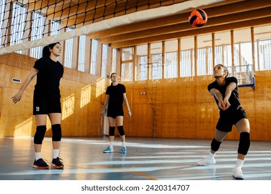 Multicultural female teenage volleyball players are hitting and passing the ball on training and practicing volleyball on indoor court. Professional interracial young sportswomen practicing volleyball - Powered by Shutterstock