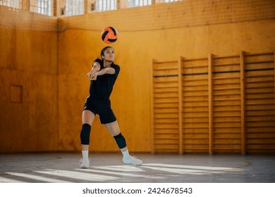 A multicultural female volleyball player in motion hitting and passing a ball on court during the training. A young teenage sportswoman is practicing volleyball while hitting and passing it on court. - Powered by Shutterstock