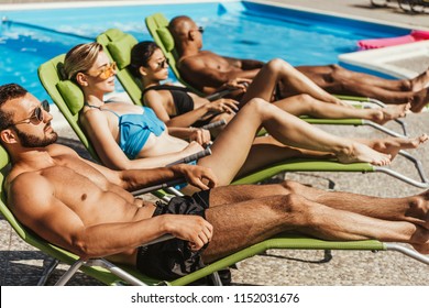 multicultural friends in swimsuits sunbathing on sunbeds at poolside, selective focus - Powered by Shutterstock