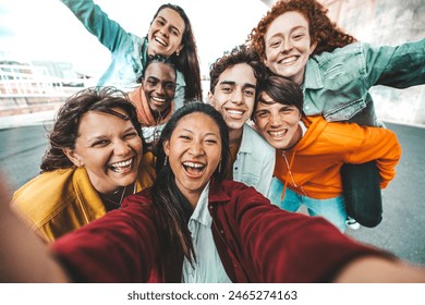 Multicultural friends taking selfie with smart mobile phone outside - Happy young people smiling together at camera - Technology and youth culture concept - Powered by Shutterstock