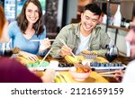 Multicultural gen z friends eating sushi with chopsticks at fusion restaurant winery - Food and beverage life style concept with happy people having fun together at eatery bar - Bright vivid filter