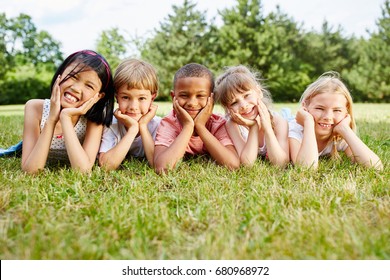 Multicultural group of children lie on grass and rest during school trip